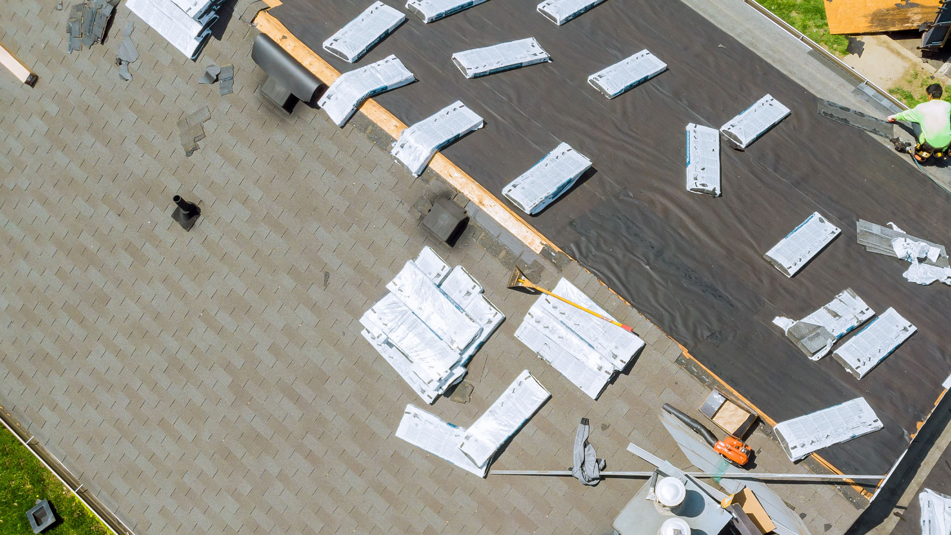 Asphalt shingle roof being installed with underlayment and materials on site